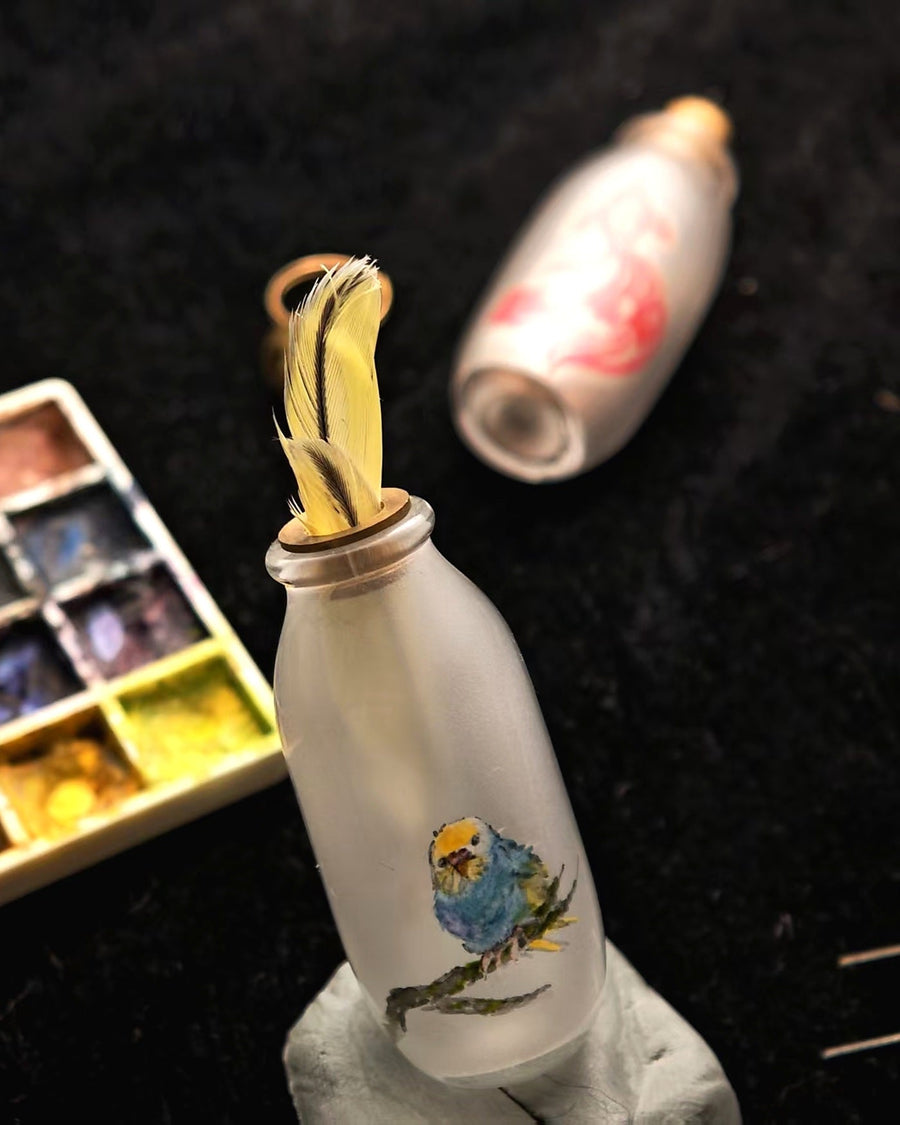 Custom bird feather keepsake with an inside-painted bird portrait and gold-tone closure