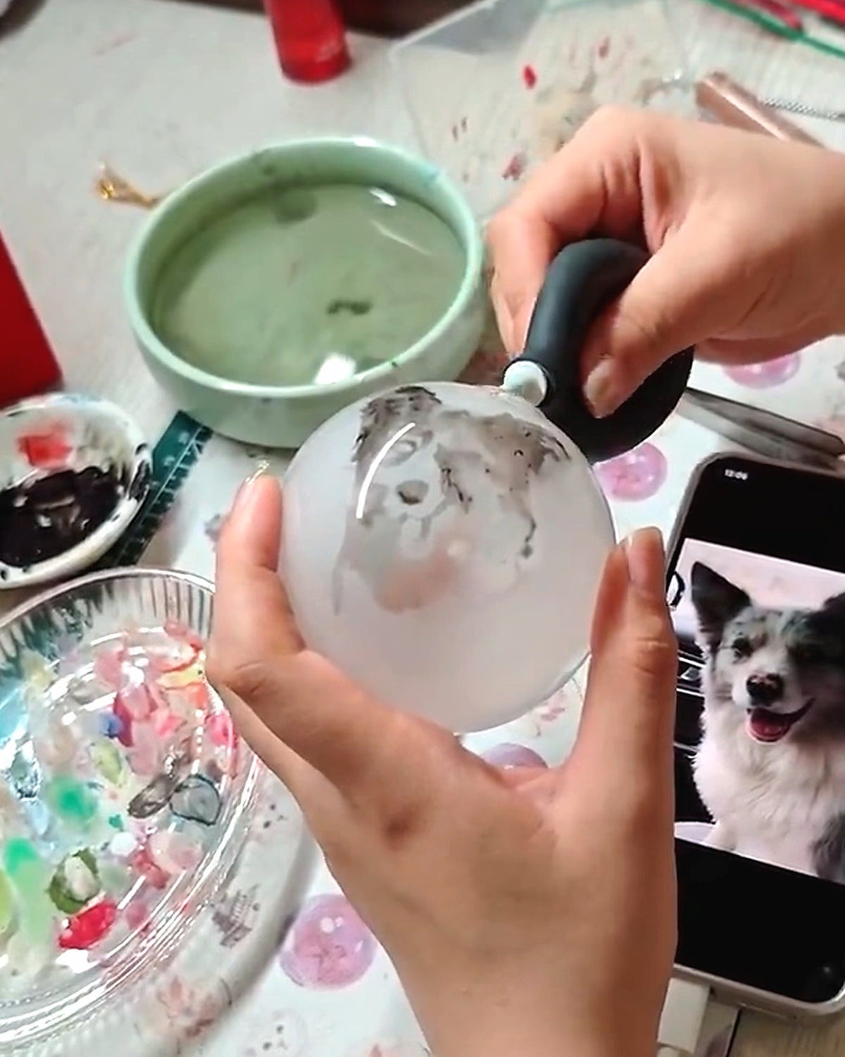 Inside-painting artist guiding a hooked brush through clear glass to paint a custom pet portrait