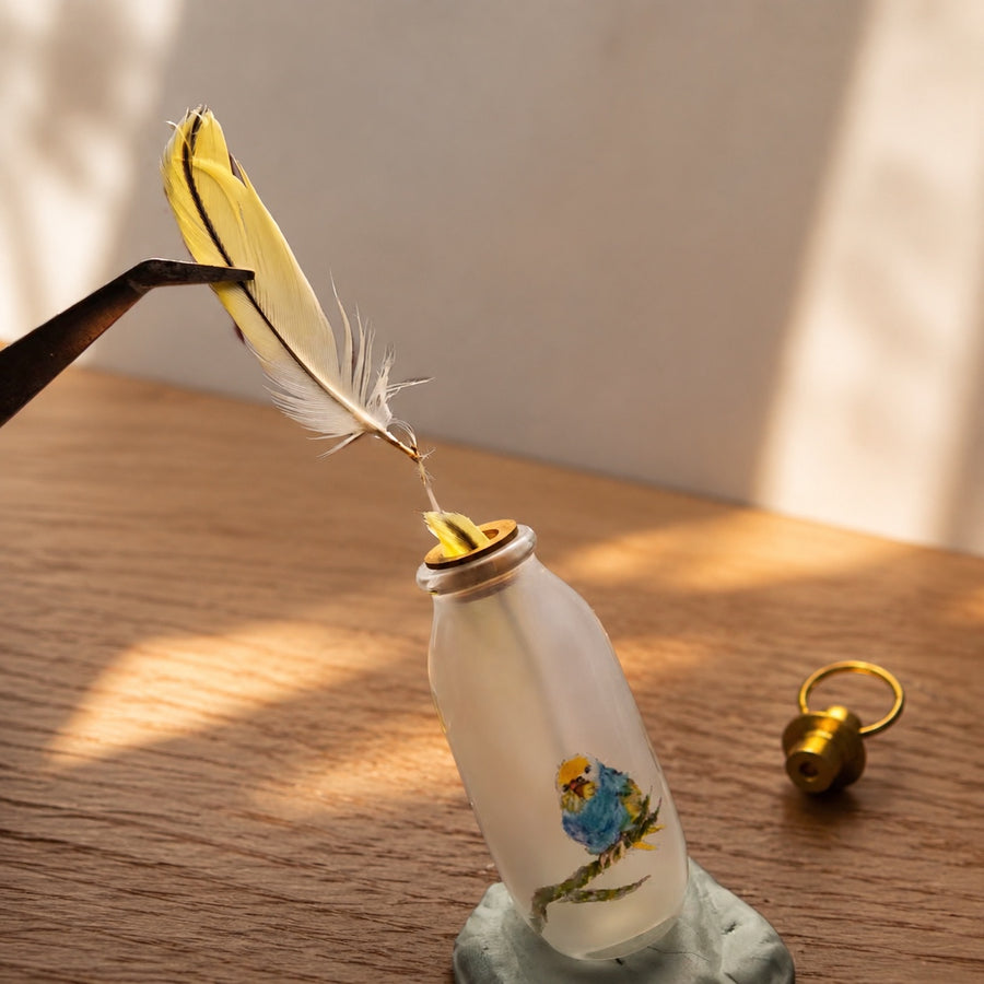Small clean bird feather being placed inside a custom hand-painted glass keepsake