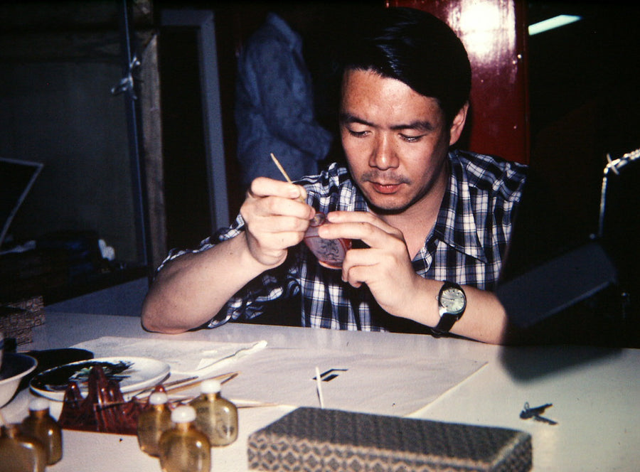 Artist guiding a hooked brush inside a glass keepsake
