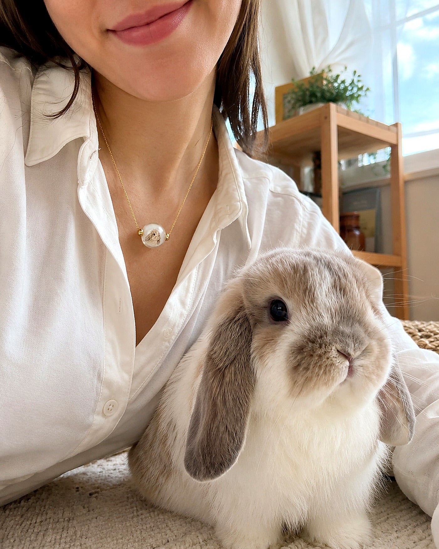 Custom pet portrait necklace worn beside a pet rabbit